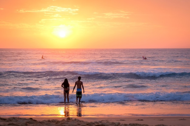 Silhouetten von Menschen am Strand gegen den Himmel beim Sonnenuntergang