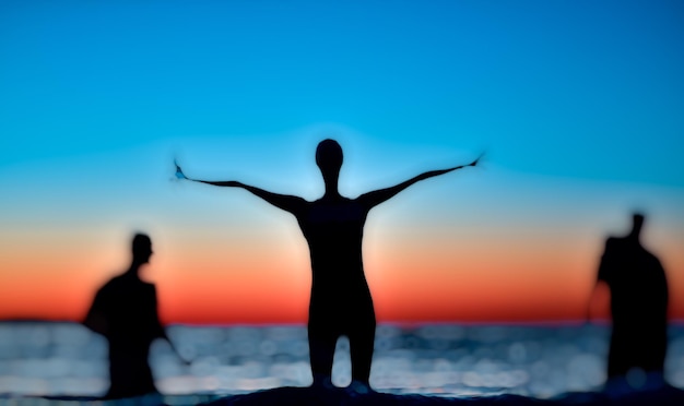 Foto silhouetten von menschen, die bei sonnenuntergang am meer vor klarem himmel stehen