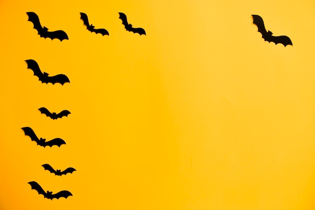 Silhouetten von schwarzen Fledermäusen aus Papier auf orangefarbenem Hintergrund. Halloween-Konzept