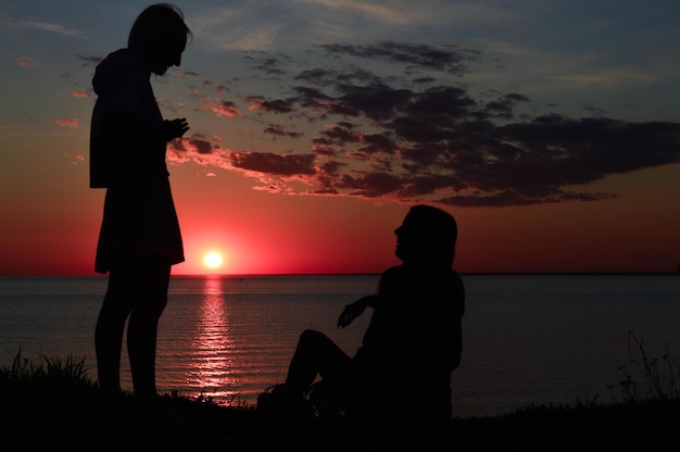 Silhouetten von zwei Mädchen am Strand am Meer