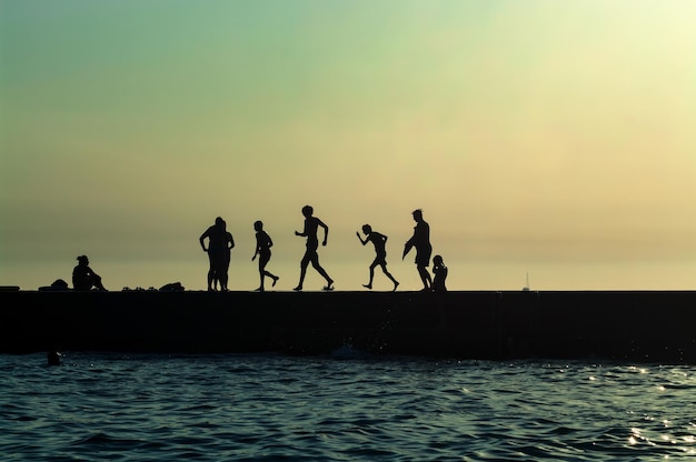 Silhouettenfoto von Menschen, die sich nach Sonnenuntergang auf dem Pier ausruhen