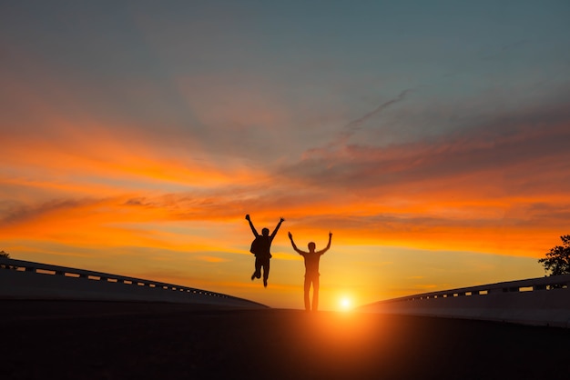 Silhouettenpaare, die bei Sonnenuntergang springen