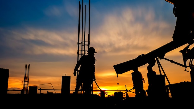 Silhouettieren Sie den Bauarbeiter Beton, der während der Betonierbetonungsböden des Gebäudes in der Baustelle gießt