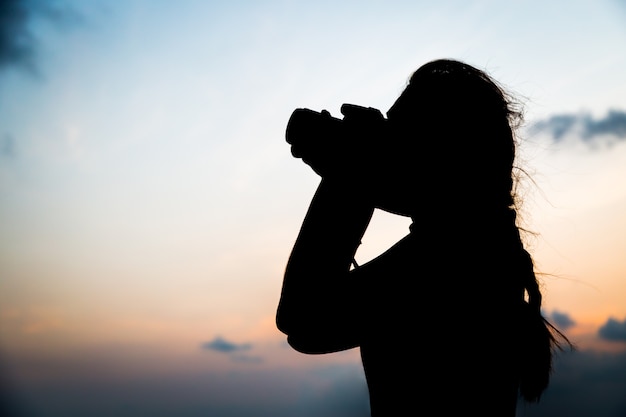Silhouettieren Sie den Fotografen, der ein Foto auf Sonnenunterganghintergrund macht