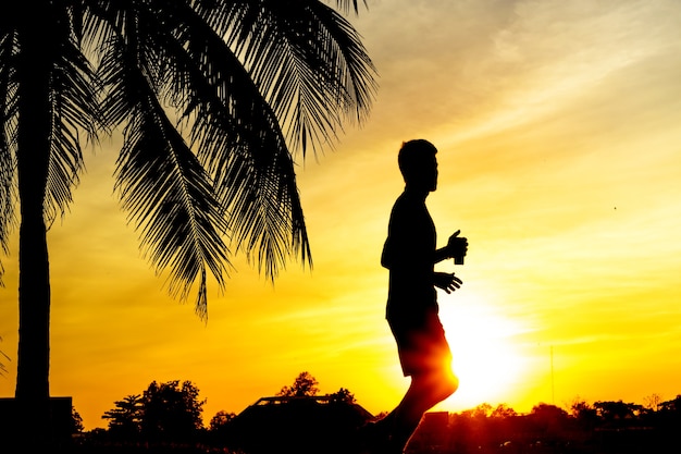 Silhouettieren Sie einen Mann, der für Übung bei Sonnenuntergang rüttelt.