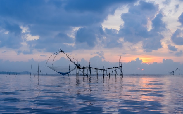 Silhouettieren Sie Fischernetzfalle am Sonnenaufgangmeerblick in Phatthalung, Thailand