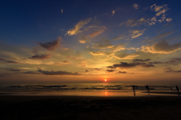 Silhouettieren Sie Leute am Sonnenuntergangstrand mit orange Himmel mit schönem Blau