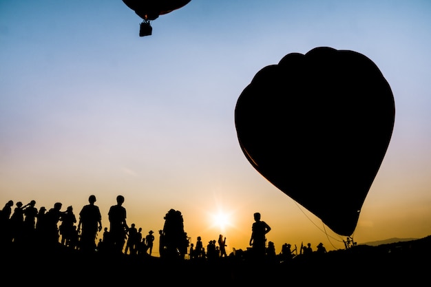 Silhouettieren Sie Leute im Ballonfestival auf schönem Sonnenunterganghimmel am Singha-Park