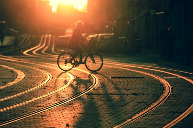 Silhueta borrada de bicicleta de equitação de mulher durante o pôr do sol na cidade de Bordeaux em estilo vintage