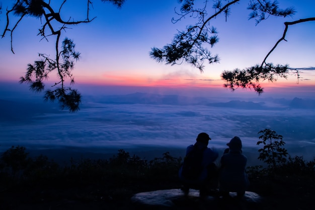 silhueta Casal romântico e sentar e assistir o nascer do sol na montanha.