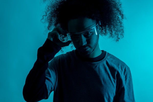 Silhueta com luz azul com óculos led futuristas Jovem com cabelo afro em fundo branco