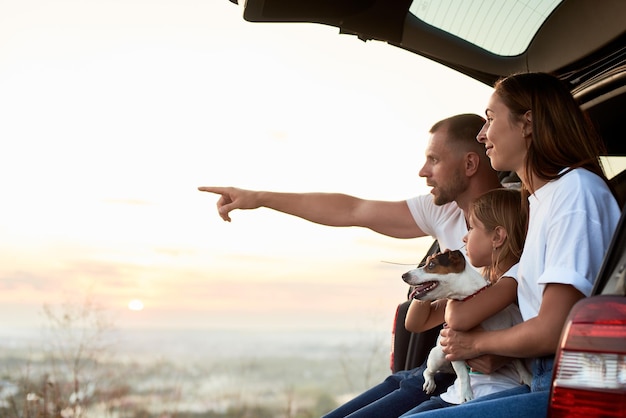 Foto silhueta da família em uma mala de carro no pôr do sol