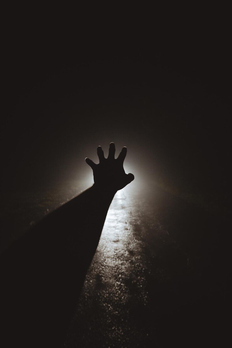 Foto silhueta da mão de uma pessoa fazendo gestos na rua à noite