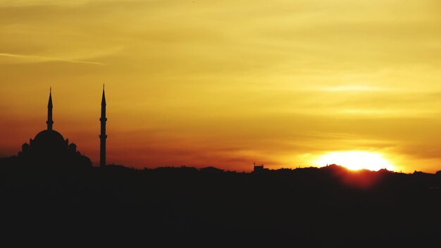 Foto silhueta da mesquita contra o céu nublado durante o pôr do sol