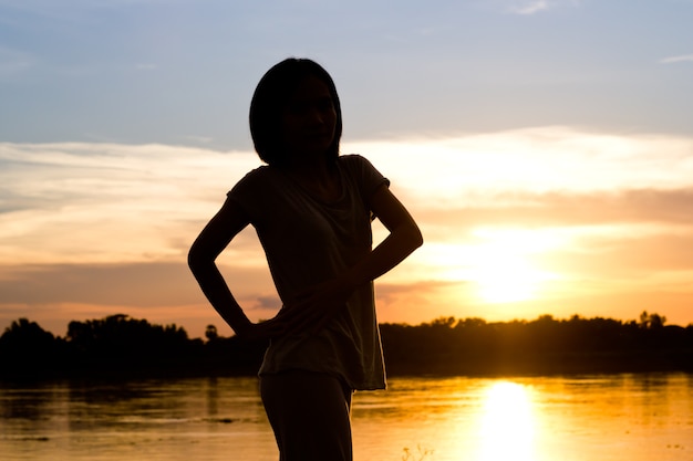 Silhueta da mulher que exercita sobre o fundo bonito do por do sol.