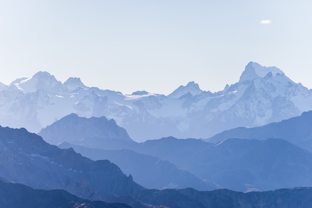 Silhueta de alta montanha em tons azul, espantosa ao pôr do sol, os Alpes