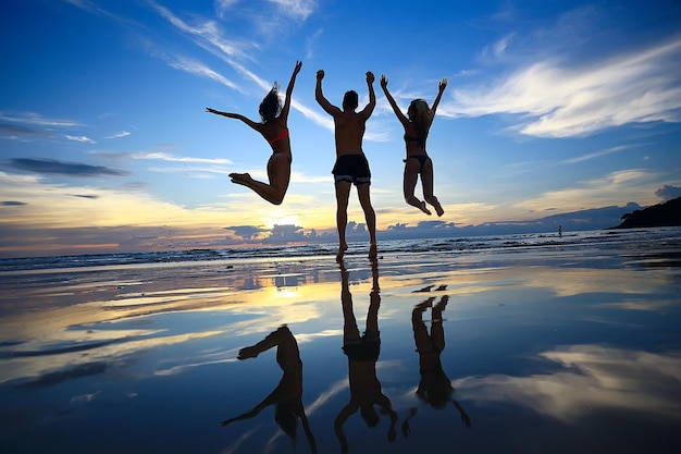 silhueta de amigos pôr do sol mar verão / grupo de jovens amigos homens e mulheres no verão descansar e se divertir no mar, feliz pôr do sol do mar