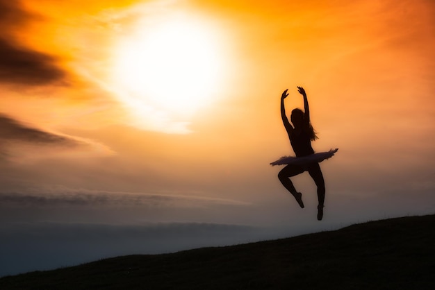 Silhueta de bailarina dançando sozinha na natureza nas montanhas ao pôr do sol