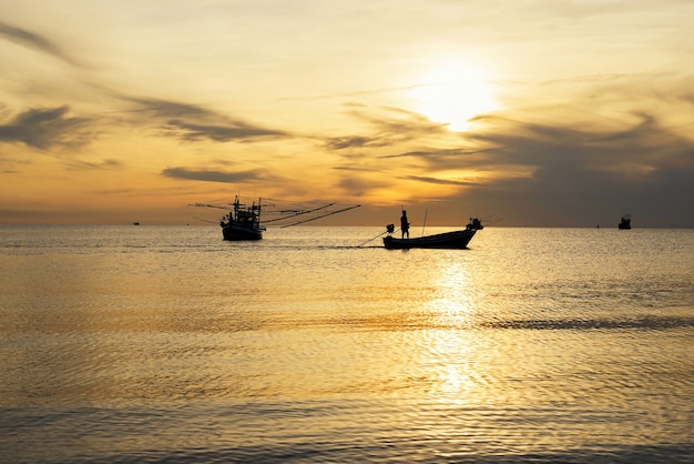 Silhueta de barco de pesca no mar com fundo do nascer do sol da manhã