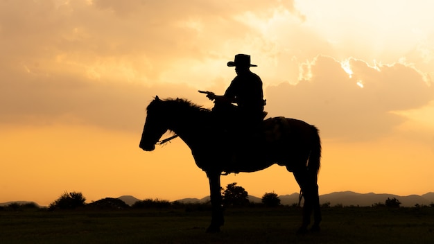 Foto silhueta de cowboy a cavalo contra um lindo pôr do sol