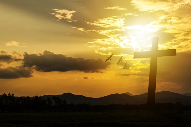 Foto silhueta de cruz no fundo do pôr-do-sol da montanha