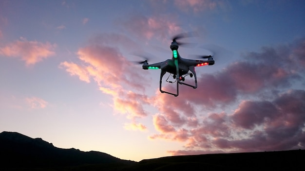 Silhueta de drone acima das colinas no céu à noite.