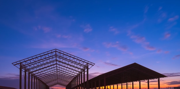 Silhueta de duas estruturas industriais metálicas contra o fundo do céu ao pôr-do-sol em vista panorâmica