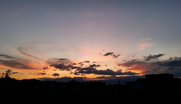 Silhueta de edifícios contra o céu nublado durante o pôr do sol