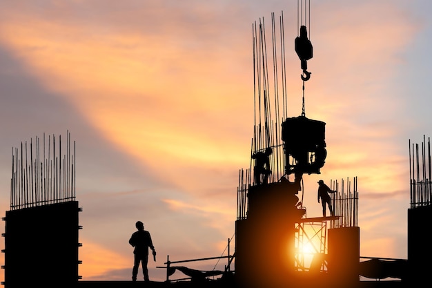 Silhueta de engenheiro e trabalhador verificando projeto no canteiro de obras