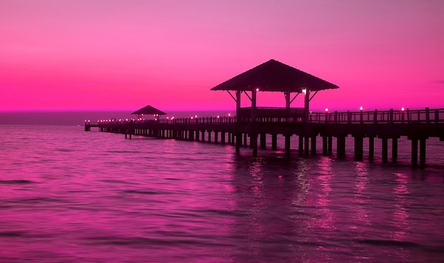 Silhueta de estilo pop art do pavilhão de madeira no cais ao pôr do sol em tom rosa roxo vívido