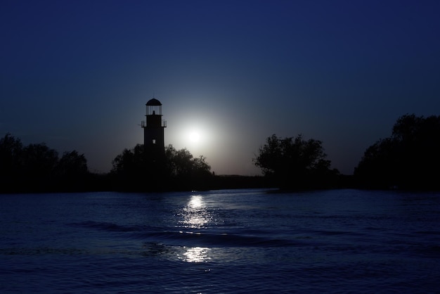 Silhueta de farol antigo ao pôr do sol em SulinaRomania