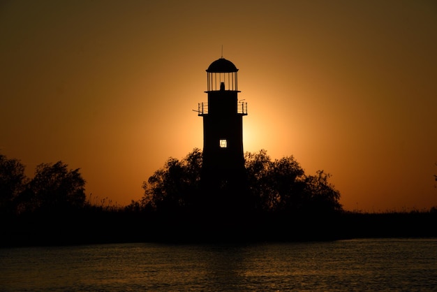 Silhueta de farol antigo ao pôr do sol em SulinaRomania