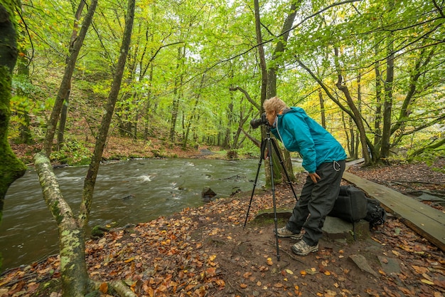 Silhueta de fotógrafo profissional tirando foto do rio na floresta