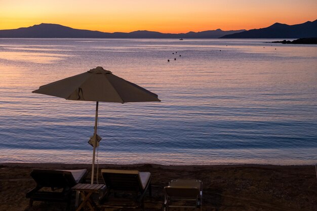 Foto silhueta de guarda-chuva de vime na praia arenosa de stoupa ao pôr do sol mani messenia grécia peloponeso