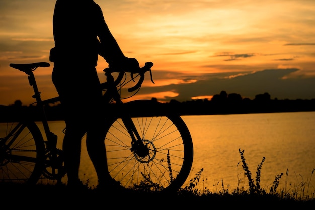 Silhueta de homem asiático andar de bicicleta no pôr do sol