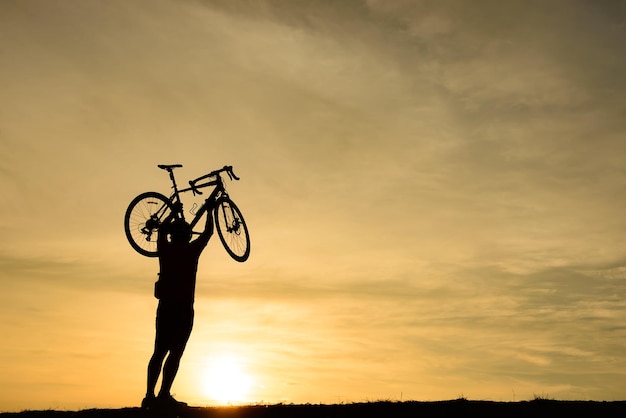 Silhueta de homem bonito com bicicleta no conceito de homem por do sol