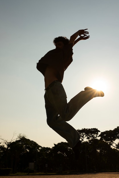Foto silhueta de homem de tiro completo pulando ao pôr do sol
