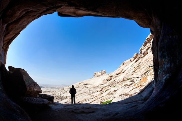 Silhueta de homem na frente de uma entrada de caverna