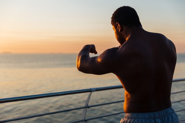 Silhueta de jovem atleta sério boxeando ao ar livre ao nascer do sol