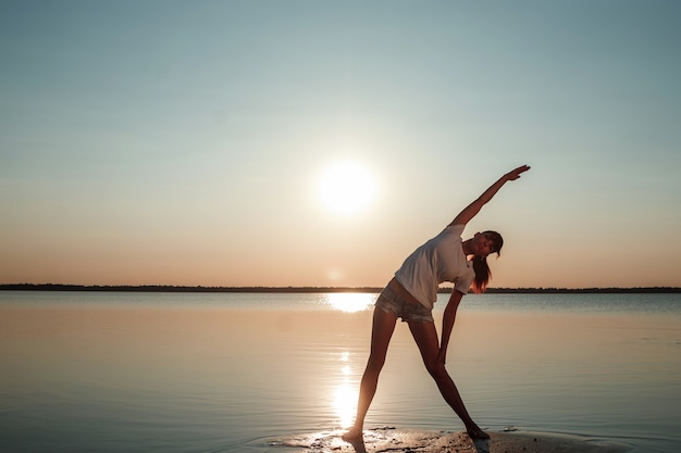 Silhueta de jovem em um lago e pôr do sol