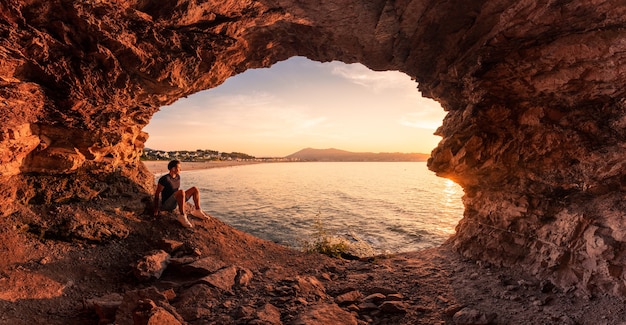 Silhueta de jovem em uma caverna costeira ao lado da praia de Hendaia, no País Basco.