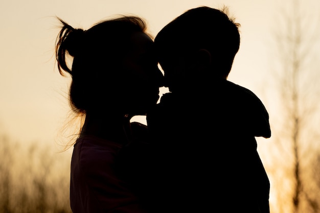 Silhueta de mãe e filho brincando ao ar livre ao pôr do sol