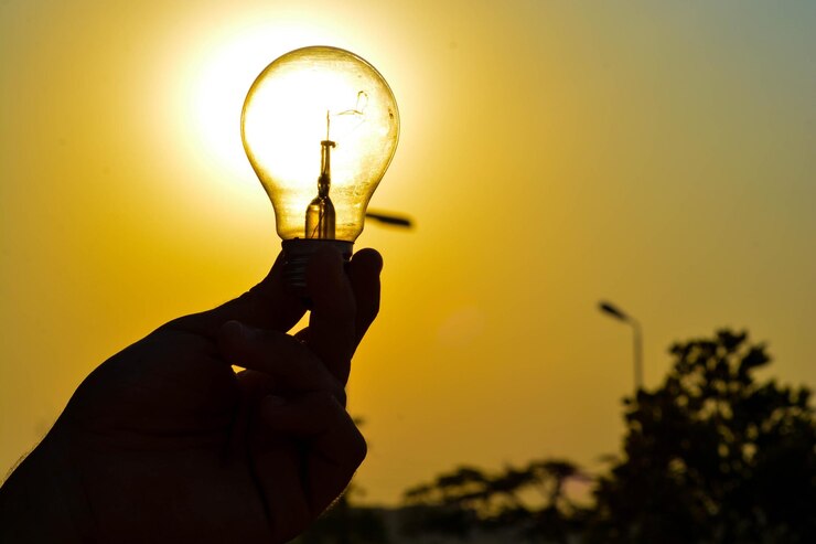 Foto silhueta de mão segurando uma lâmpada contra o céu durante o pôr do sol