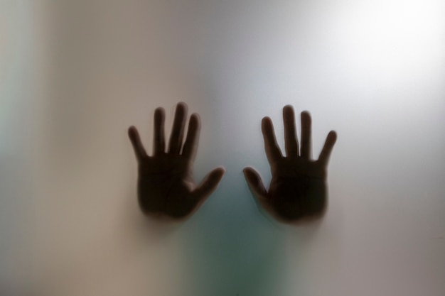 Silhueta de mãos atrás do vidro fosco conceito de pedir ajuda e violência doméstica