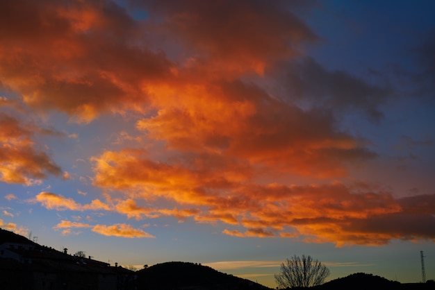 Silhueta de montanha do sol com nuvens laranja