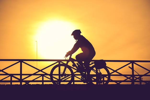 Silhueta de motociclista na ponte e pôr do sol cor vintage