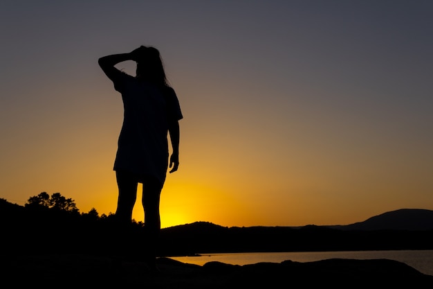 Foto silhueta de mulher ao pôr do sol olhando o horizonte superando as dificuldades da vida copie o espaço