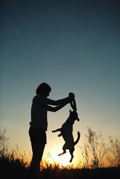 Silhueta de mulher brincando com um cachorro