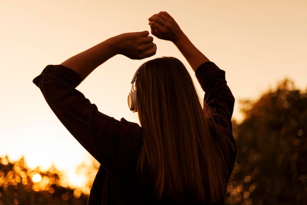 Foto silhueta de mulher com fones de ouvido ao pôr do sol