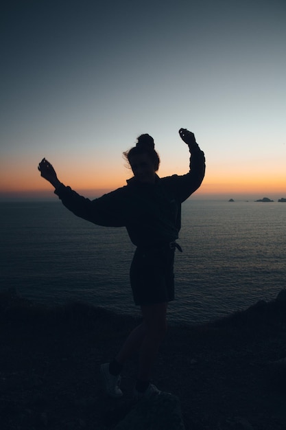 Foto silhueta de mulher dançando na praia contra o céu durante o pôr do sol